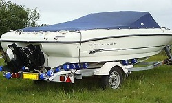 a grassed area containing a trailer with a speedboat